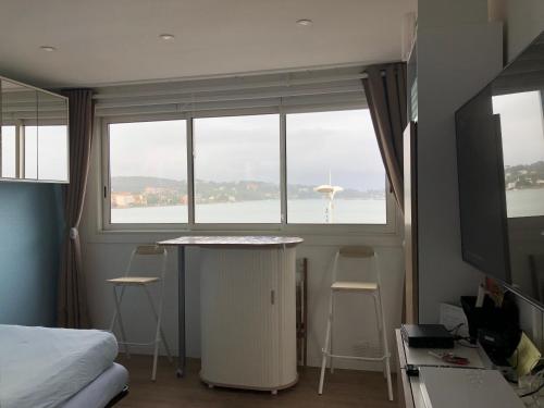 a room with a bed and a window with a table and chairs at Studio Bord de Mer et VUE sur MER WIFI OFFERT in La Seyne-sur-Mer