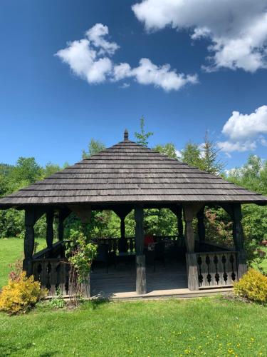a wooden gazebo in a field of grass at Dwór na Wrzosowisku in Cisna