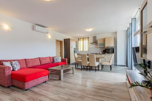 a living room with a red couch and a kitchen at Apartment Livia in Cres