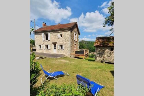 two blue chairs in the yard of a house at Gîte Les Hauts de Villemaloux in Dontreix