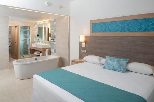 a bedroom with a large bed and a bath tub at Riu Palace Tropical Bay - All Inclusive in Negril