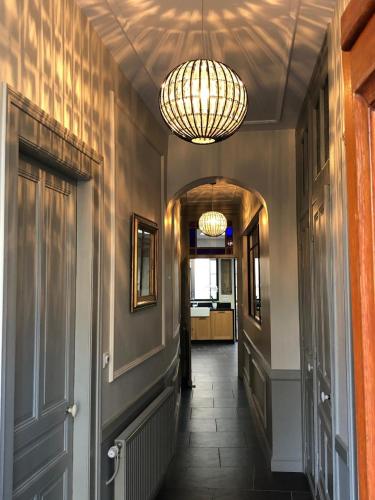 a hallway with two chandeliers and a hallway with a hallwayngth at Les chambres Berguoises Chambre Rez-de-chaussée au coeur de Bergues in Bergues