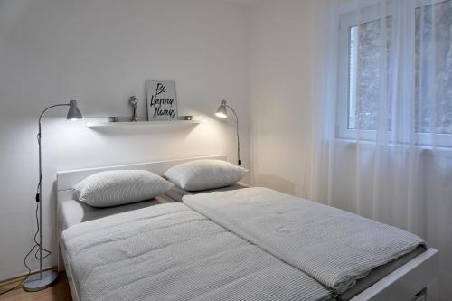 a white bedroom with a bed with two pillows at Del Mar Rabac in Rabac