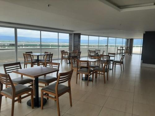 a dining room with tables and chairs and windows at Flat Kariris Home Service in Juazeiro do Norte