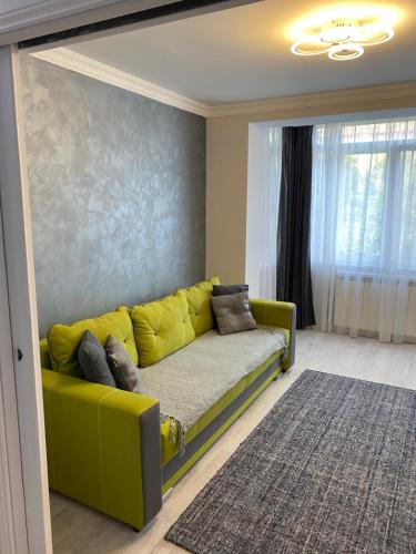 Sofá amarillo en la sala de estar con alfombra en Gabi Apartament, en Suceava