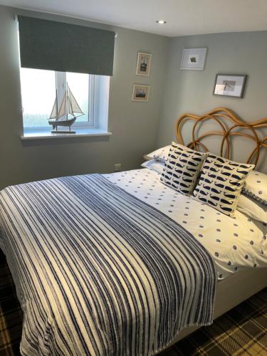 a bed with a striped comforter in a bedroom at Tiny Beach House in Saint Annes on the Sea