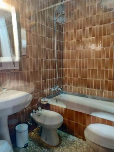 a bathroom with a toilet and a sink and a tub at Covas Beach Arena in Viveiro