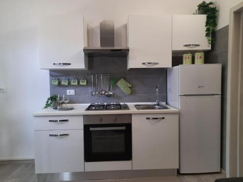 cocina con armarios blancos, fogones y nevera en Marco's apartment -ideale per Venezia- en Mestre