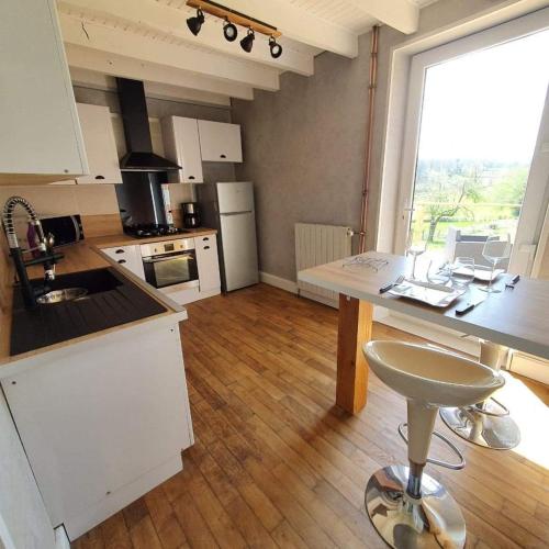 a kitchen with white cabinets and a large window at Gîte Les Hauts de Villemaloux in Dontreix