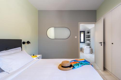 a bedroom with a white bed with a hat on it at Minois Boutique Hotel in Stalida