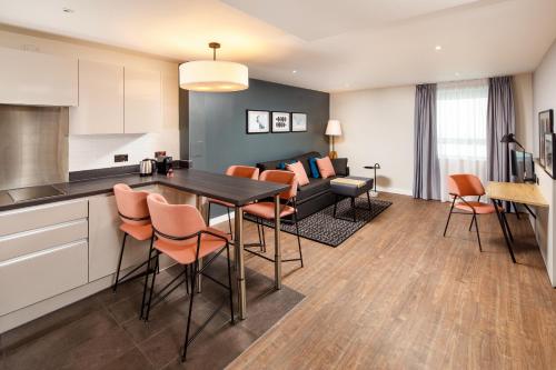 a kitchen and living room with a table and chairs at Aparthotel Adagio London Sutton Point in Sutton