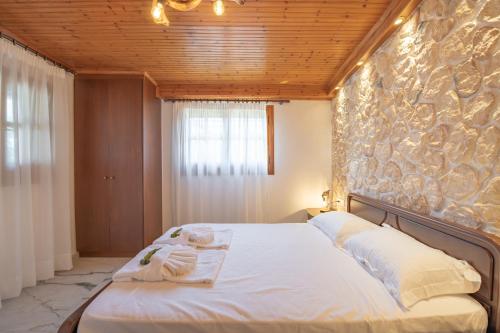 Un dormitorio con una cama con una pared de piedra. en Villa Yiannitsis - Sunset by the Sea, Acharavi Beach, en Acharavi