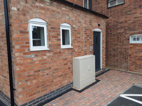 a brick wall with a refrigerator in front of a building at 27 High Street Apartments in Husbands Bosworth