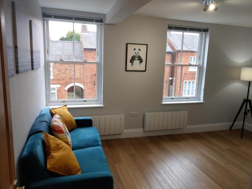 a living room with a blue couch and two windows at 27 High Street Apartments in Husbands Bosworth