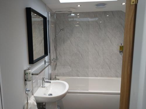 a bathroom with a sink and a bath tub with a mirror at 27 High Street Apartments in Husbands Bosworth