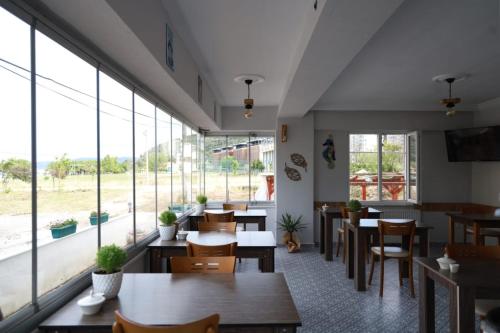 un restaurante con mesas, sillas y ventanas grandes en Eceabat Doğa Pansiyon-Hotel, en Eceabat