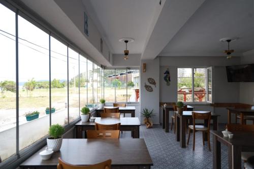 a restaurant with tables and chairs and large windows at Eceabat Doğa Pansiyon-Hotel in Eceabat