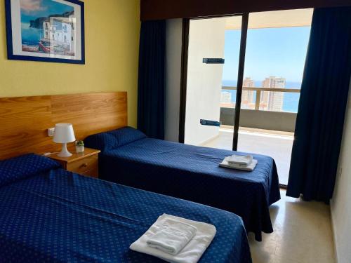 a hotel room with two beds and a large window at Apartamentos Gemelos 2 y 4 by Gestaltur in Benidorm