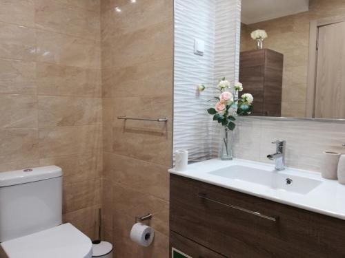 a bathroom with a sink and a toilet and flowers at Amoreira Mar, Alvor - Praia e Piscina in Alvor