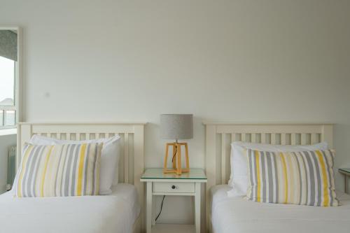 a bedroom with two beds and a table with a lamp at The Eyre Square Townhouse in Galway