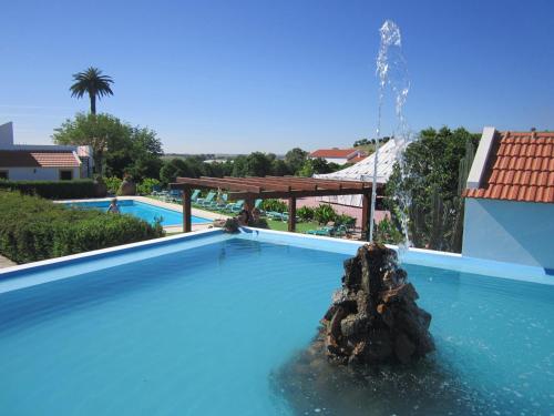 a swimming pool with a fountain in the middle of it at Horta Da Vila in Alvito