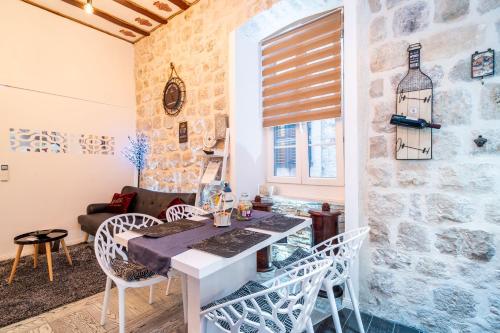 een kamer met een tafel en stoelen en een stenen muur bij Kaboga Palace Luxury apartment in Dubrovnik