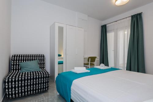 a bedroom with a bed and a chair at Apartmani Ujakovic in Kaštela