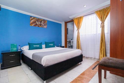 1 dormitorio con cama y pared azul en Ayenda Avenida Boyaca, en Bogotá