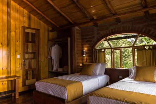 a bedroom with two beds in a wooden cabin at Casa de Vista Alta in Mindo