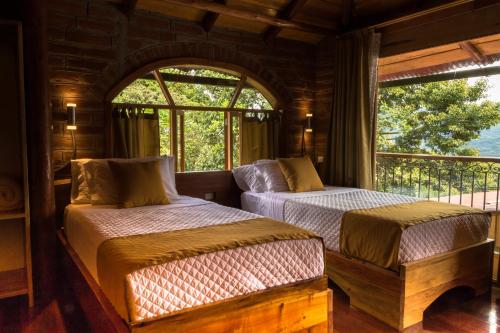 two beds in a room with a window at Casa de Vista Alta in Mindo