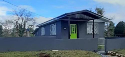 a small blue house with a green door at Casa Grey in Cambará
