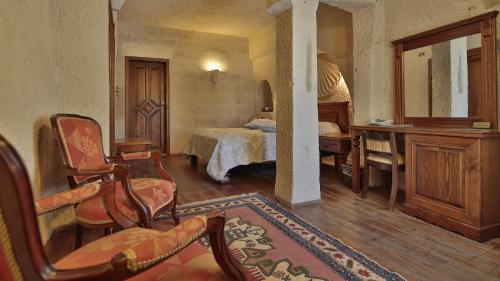a bedroom with a bed and a desk and a chair at Vezir Cave Suites in Göreme