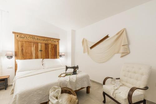 a white bedroom with a bed and a chair at B&B Antico Telaio in Santa Maria Navarrese