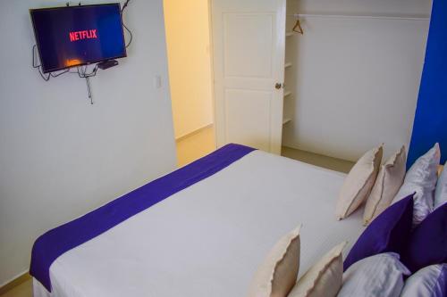 a bedroom with a bed with a tv on the wall at Hotel Checkin El Cortecito Beach in Punta Cana