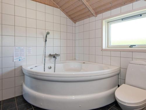 a white bathroom with a tub and a toilet at 8 person holiday home in Hemmet in Hemmet