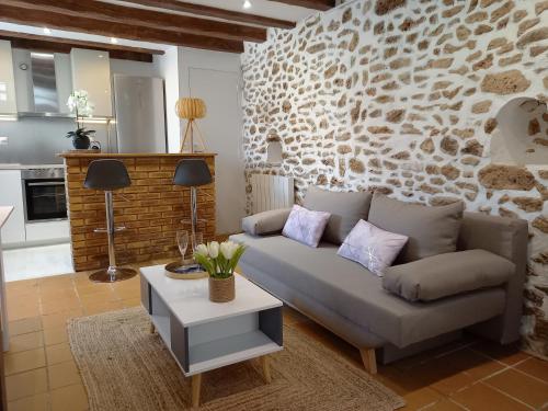 a living room with a couch and a stone wall at Charmante Maison Cosy à Villabé-Hyper Centre-Gare-WIFI in Villabé