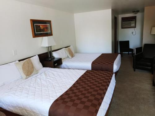 una habitación de hotel con 2 camas y una silla en Lakeshore Motel Ice Lake en Iron River