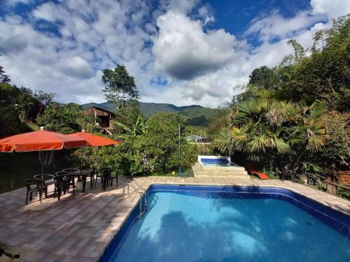 a swimming pool with a table and chairs and an umbrella at Agradable casa de Campo Villa Maruja. in Palmira