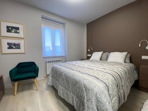 una camera con un grande letto e una sedia verde di Apartamento Puertas del Orbigo 1 a Carrizo de la Ribera