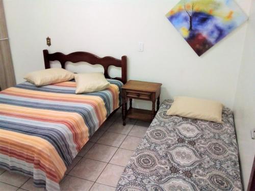 a bedroom with two beds and a table and a painting at Jardim de Londres - Sobrado em Campinas in Campinas