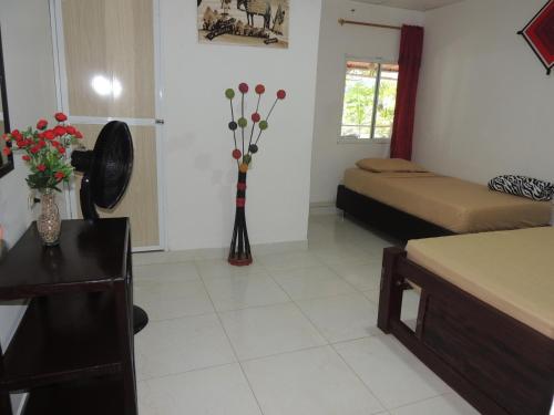 a room with two beds and a table with flowers at Hostal Alto de la Montaña in Minca