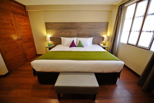 a bedroom with a large bed with a green blanket at Union Hotel Cusco in Cusco
