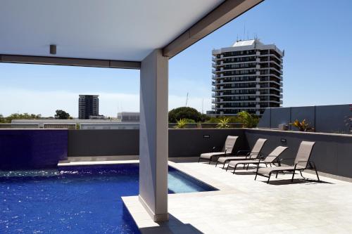 a patio with chairs and a swimming pool on a building at H on Mitchell Apartment Hotel in Darwin