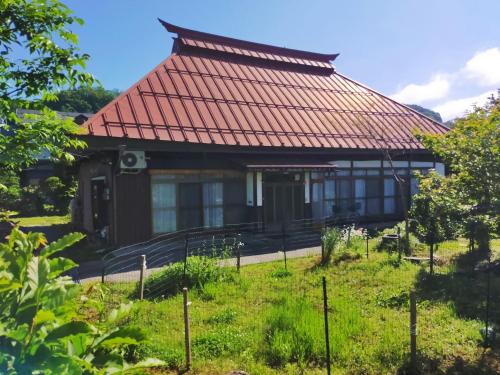 a house with a red roof in a garden at Madarao Farm in Nakano
