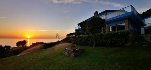 a house on a hill with the sunset in the background at Mega Ocean Magoito - Sintra in Sintra