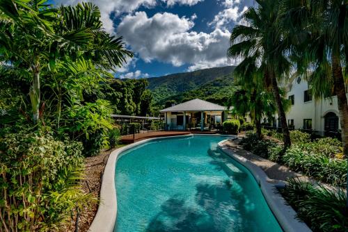 a swimming pool in front of a house with palm trees at Privately Managed Apartments in Mango Lagoon in Palm Cove