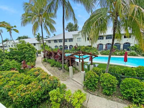 Una vista de un complejo con piscina y palmeras. en Privately Managed Apartments in Mango Resort Palm Cove, en Palm Cove