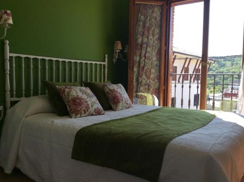 a bedroom with a bed with green walls and a window at Hotel Rural Los Roturos in Maestu
