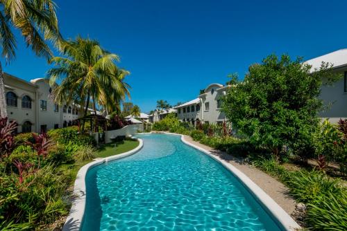 a swimming pool at a resort with palm trees and houses at Privately Managed Apartments in Mango Lagoon in Palm Cove