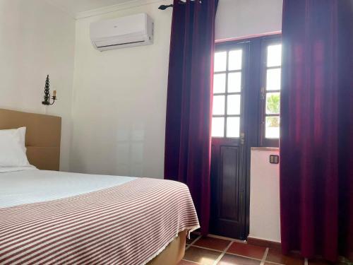 a bedroom with a bed and a window and a door at Hotel Rural A Coutada - Peniche in Atouguia da Baleia